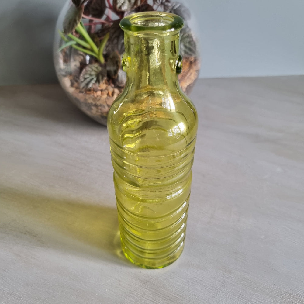 Vintage yellow-green ribbed glass bottle with small handles and retro charm.