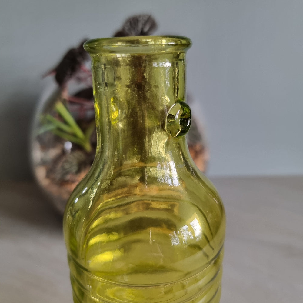 Vintage yellow-green ribbed glass bottle with small handles and retro charm.