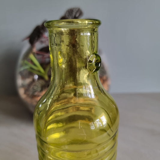Vintage yellow-green ribbed glass bottle with small handles and retro charm.