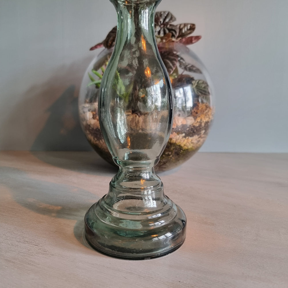 Vintage green-grey glass candlestick holder with curving shape and translucent tone.