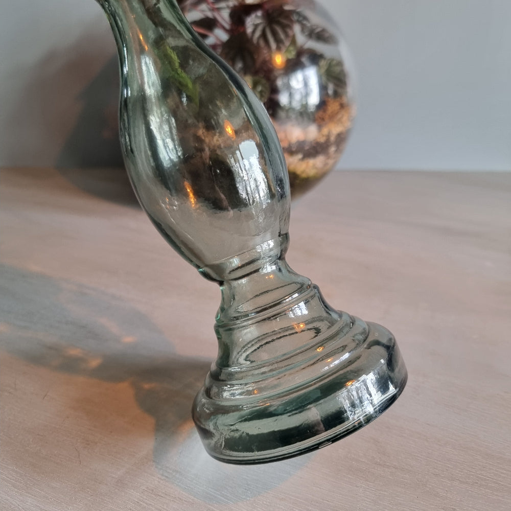 Vintage green-grey glass candlestick holder with curving shape and translucent tone.