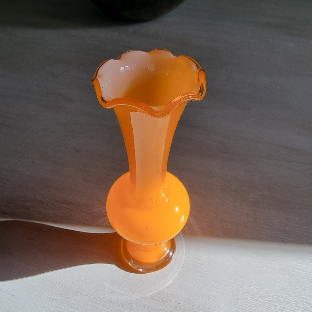 Vintage orange art glass vase with scalloped rim and bright retro tone.