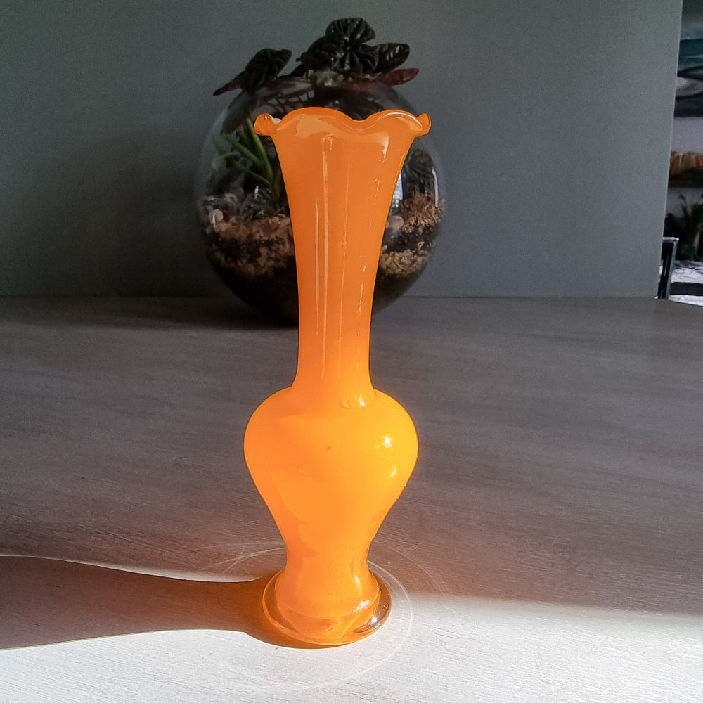 Vintage orange art glass vase with scalloped rim and bright retro tone.