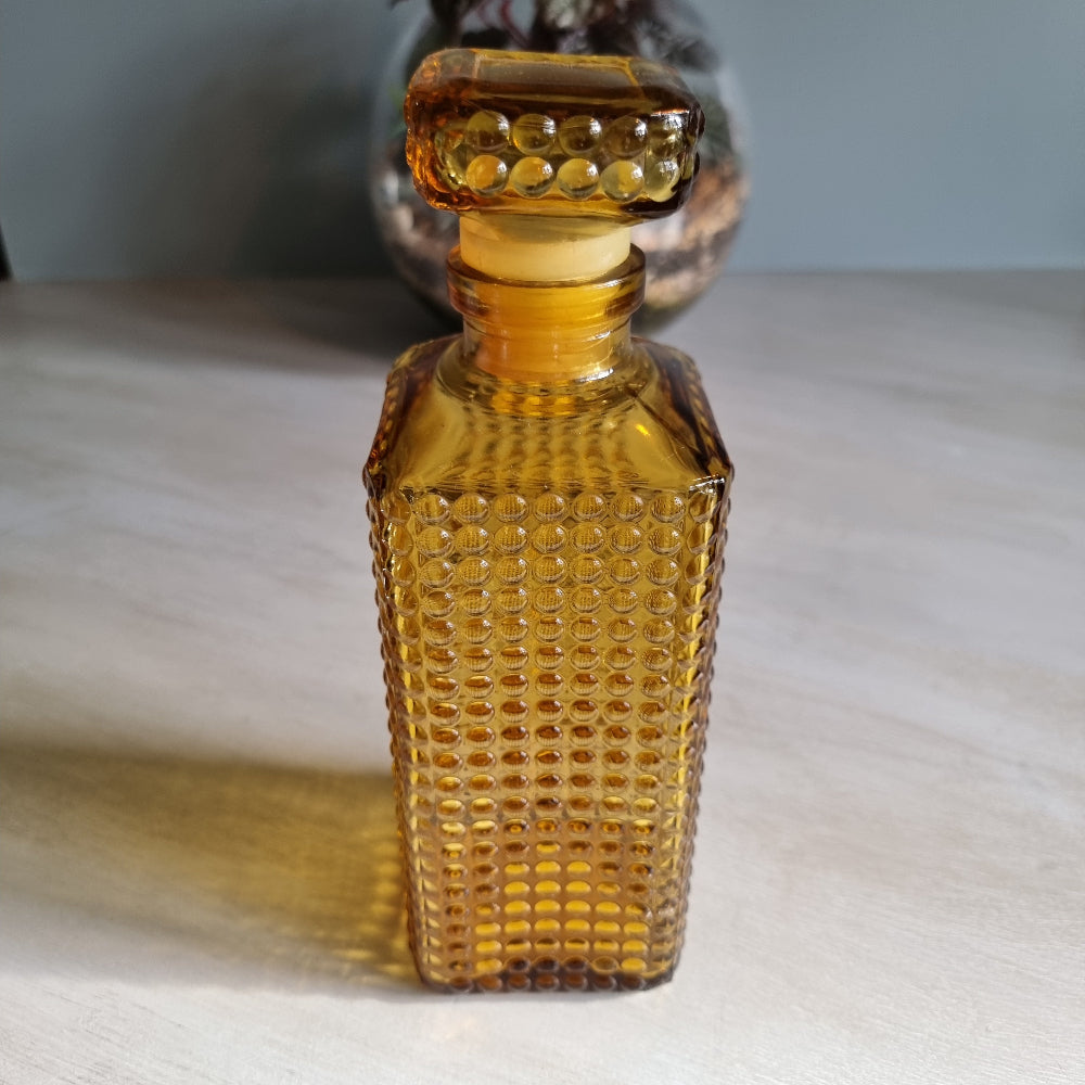 Vintage amber hobnail glass decanter with stopper and warm retro tone.