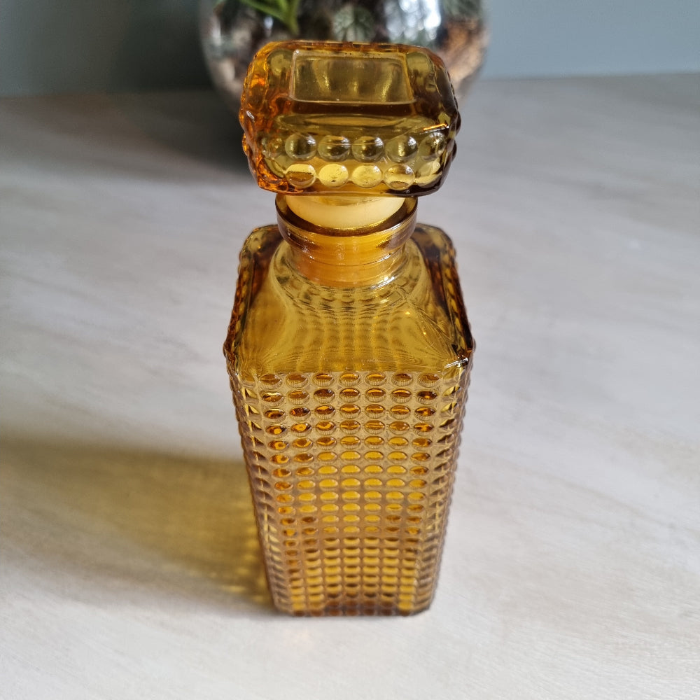 Vintage amber hobnail glass decanter with stopper and warm retro tone.