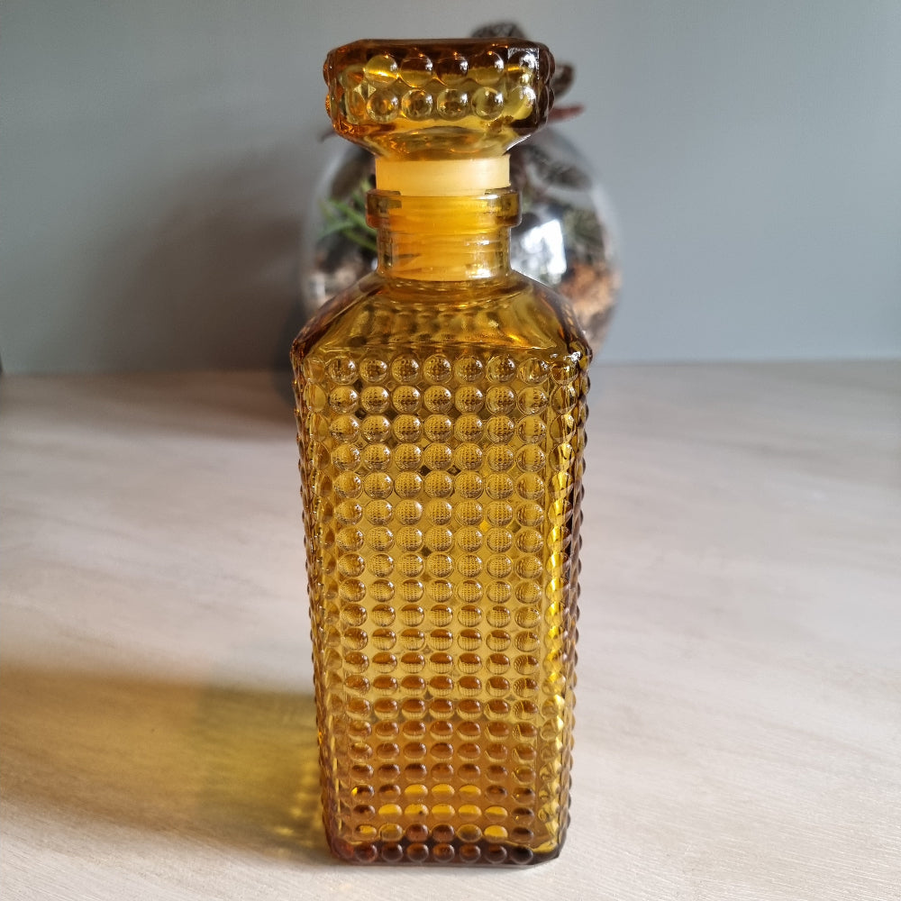 Vintage amber hobnail glass decanter with stopper and warm retro tone.