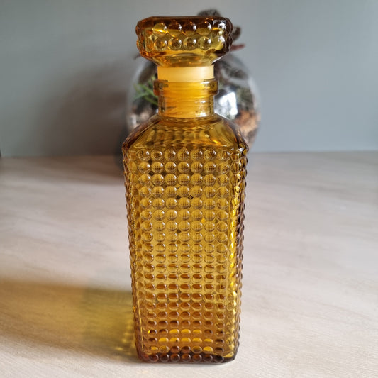 Vintage amber hobnail glass decanter with stopper and warm retro tone.