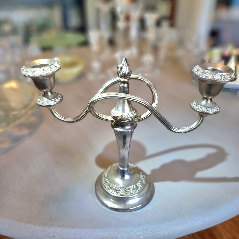 Silver two-arm candelabra with curved arms and ornate embossed detailing.