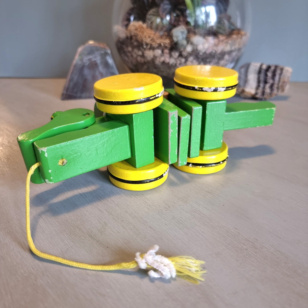 Vintage green wooden pull-along crocodile toy with yellow wheels.