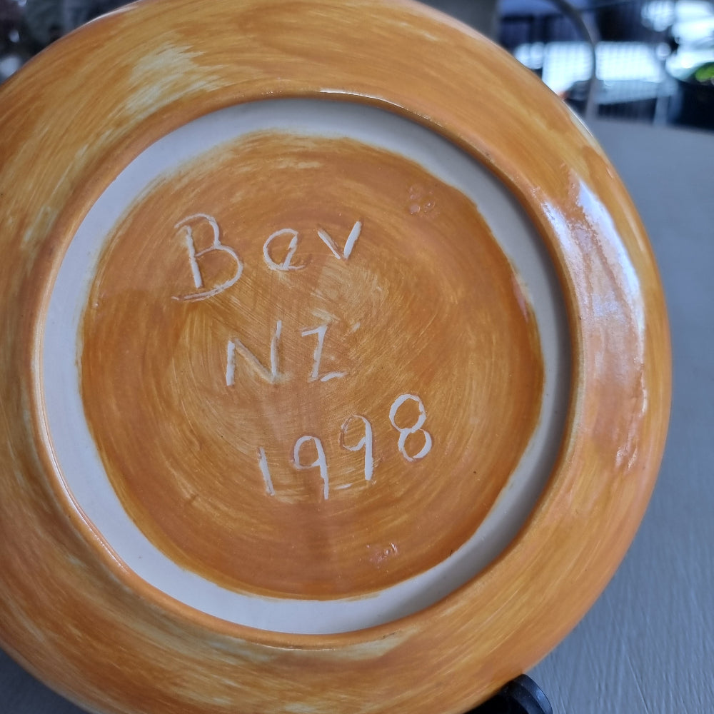 Hand painted ceramic plate with large blue flowers and green leaves signed Bev NZ 1998