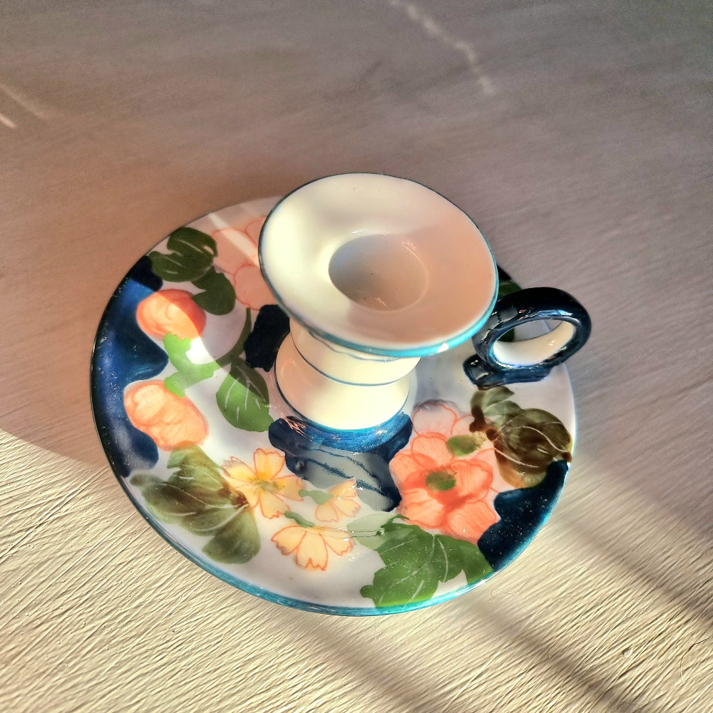 Vintage hand-painted ceramic chamberstick candle holder with coral and yellow floral design on white and periwinkle glaze, turquoise teal accent trim and loop handle