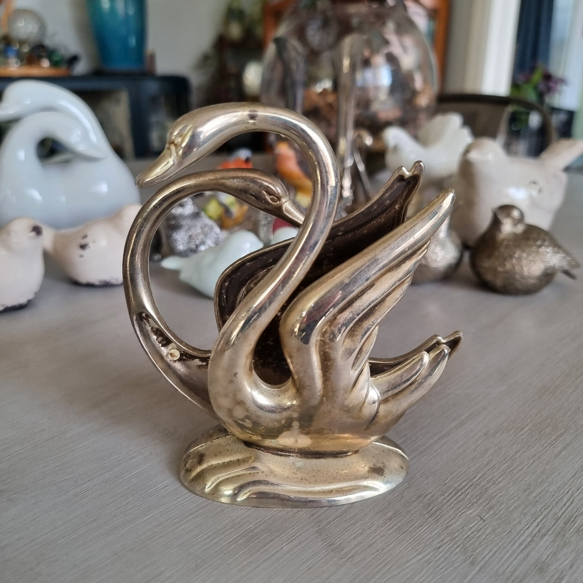 Silver swan napkin holder with sweeping feathered wings on a wave-shaped base