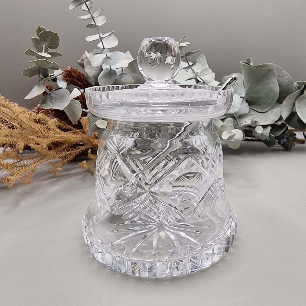 Cut glass sugar or jam jar with lid and spoon, featuring starburst pattern and faceted edge.
