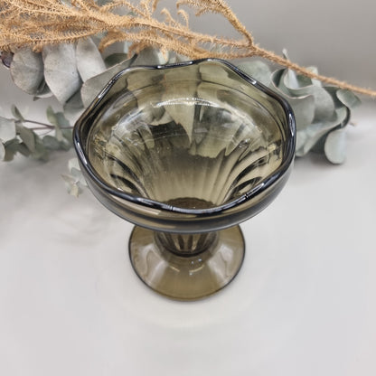 Smoky grey pedestal glass vase with fluted shape and wavy rim.
