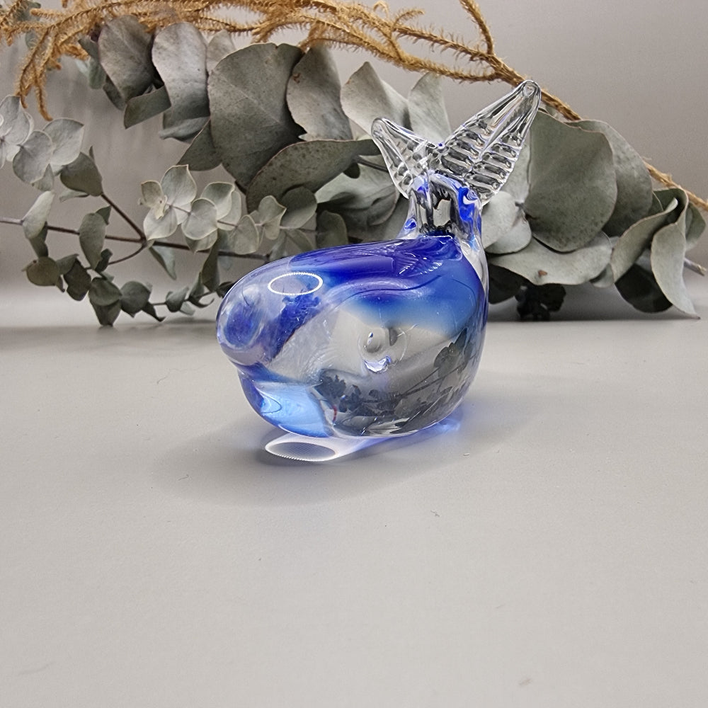 Hokitika art glass clear and blue glass whale ornament with curved tail and smooth finish.