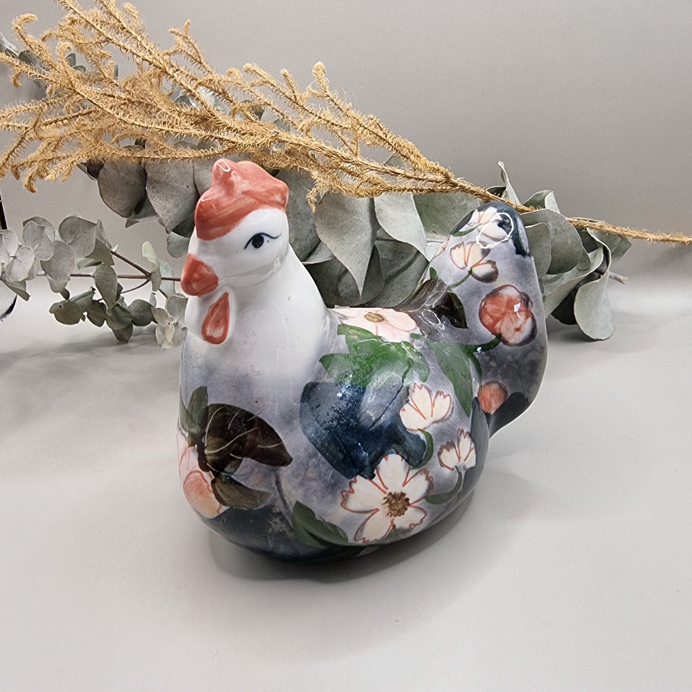 Vintage hand-painted ceramic hen figurine with soft pink and white floral design on grey and navy glaze, terracotta red comb and wattle