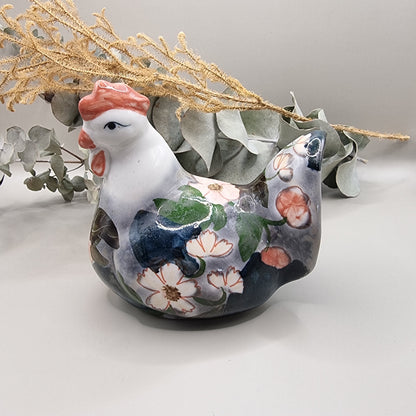 Vintage hand-painted ceramic hen figurine with soft pink and white floral design on grey and navy glaze, terracotta red comb and wattle