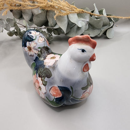 Vintage hand-painted ceramic hen figurine with soft pink and white floral design on grey and navy glaze, terracotta red comb and wattle