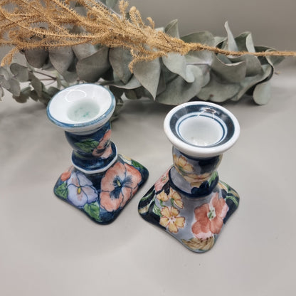 Pair of vintage hand-painted ceramic candlestick holders with pink peach and yellow floral design on navy blue glaze