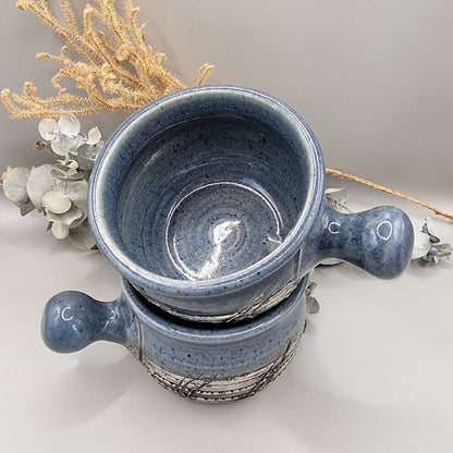 Two rustic blue soup bowls with handles and textured banding.