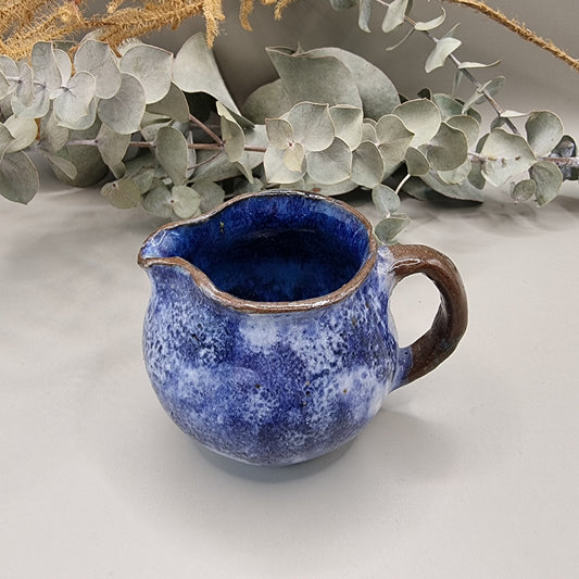 Small handmade pottery jug with cobalt blue glaze and brown handle