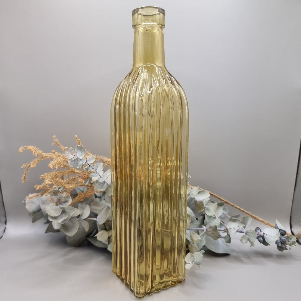 Tall yellow ribbed glass bottle with golden hue and vintage style.