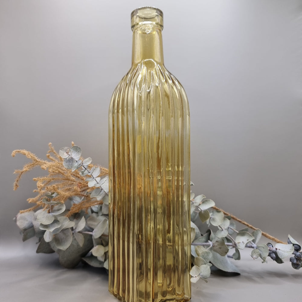 Tall yellow ribbed glass bottle with golden hue and vintage style.