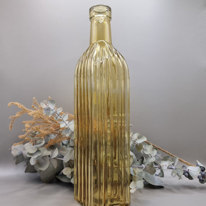 Tall yellow ribbed glass bottle with golden hue and vintage style.