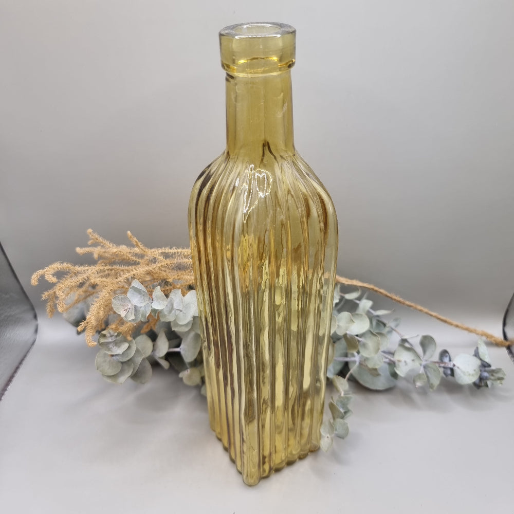 Tall yellow ribbed glass bottle with golden hue and vintage style.