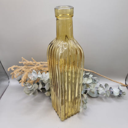 Tall yellow ribbed glass bottle with golden hue and vintage style.