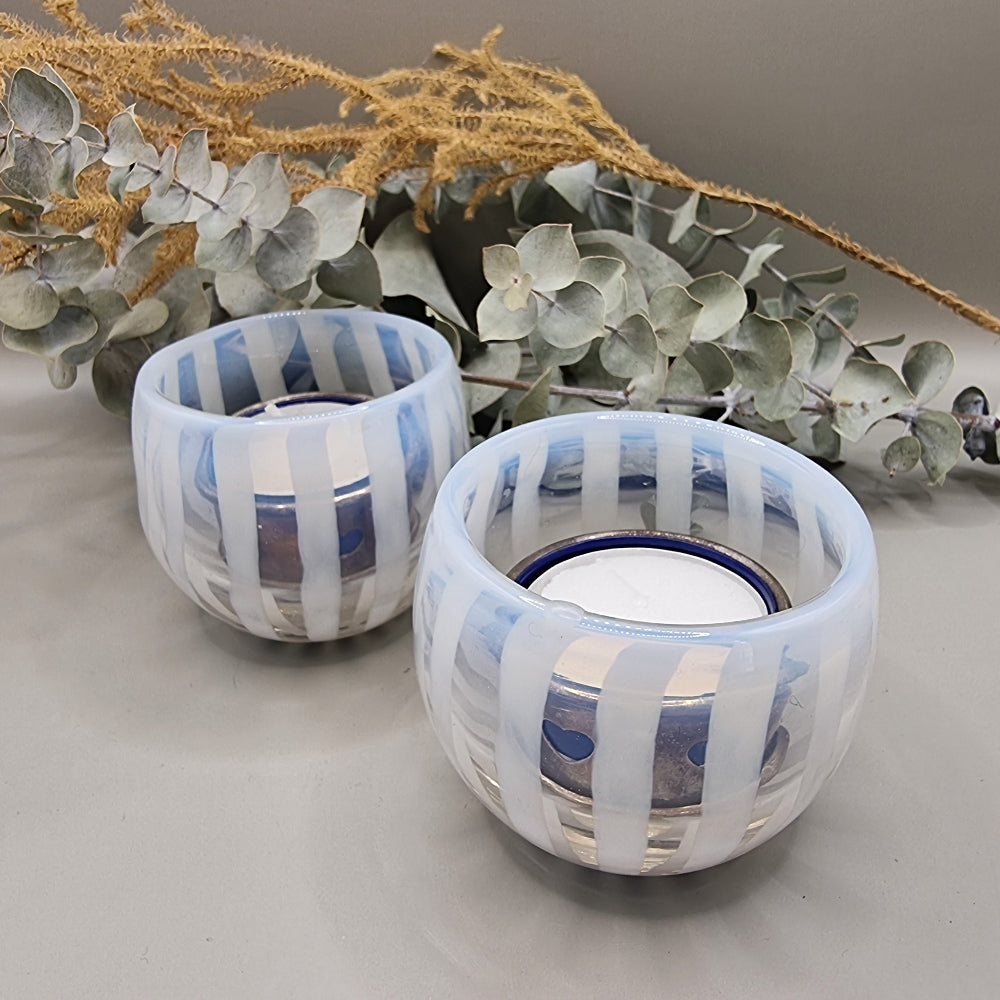 Pair of pale blue and white  striped glass tealight holders with rounded shape and white vertical bands.