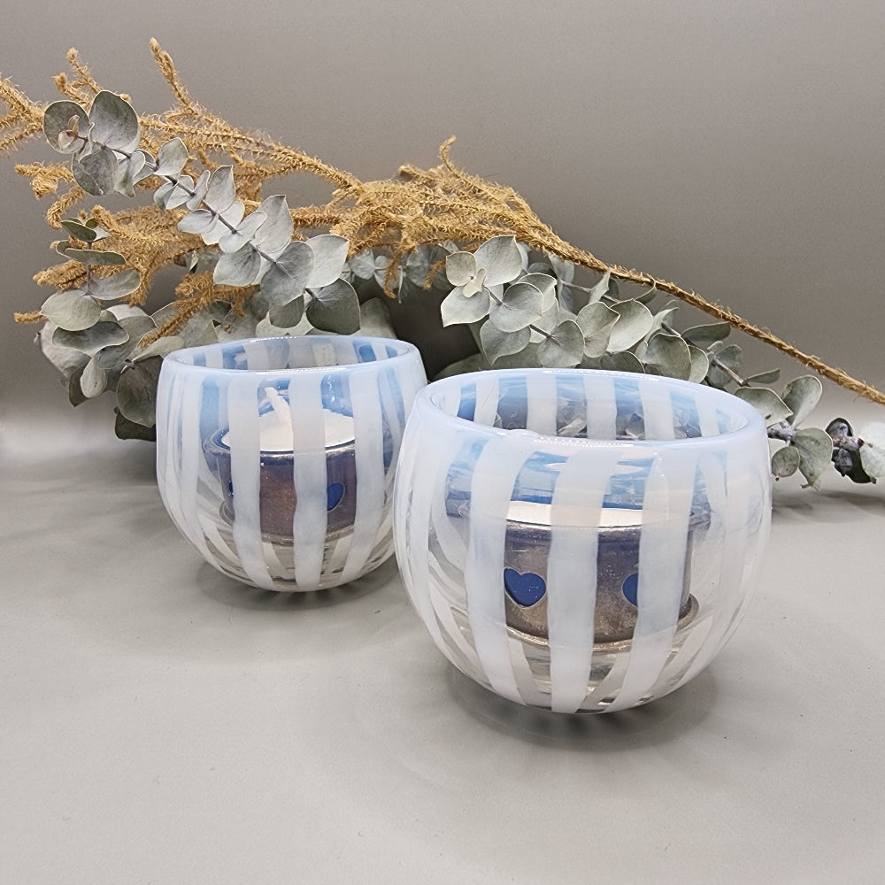 Pair of pale blue and white  striped glass tealight holders with rounded shape and white vertical bands.