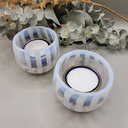 Pair of pale blue and white  striped glass tealight holders with rounded shape and white vertical bands.
