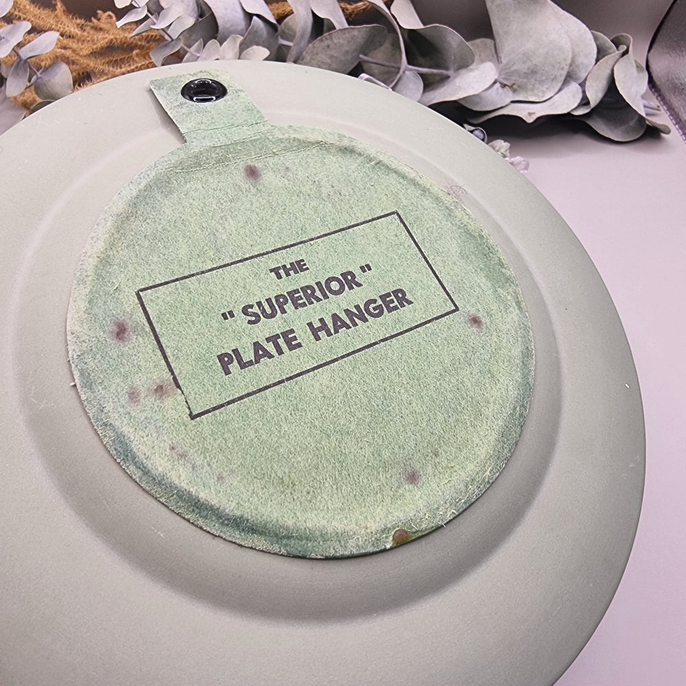 Sage green Jasperware plate with white cherub design and laurel border.