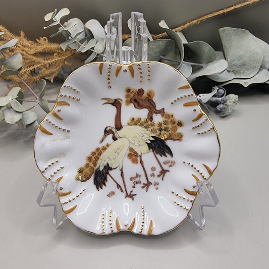 Scalloped porcelain dish with painted cranes and gold detailing.