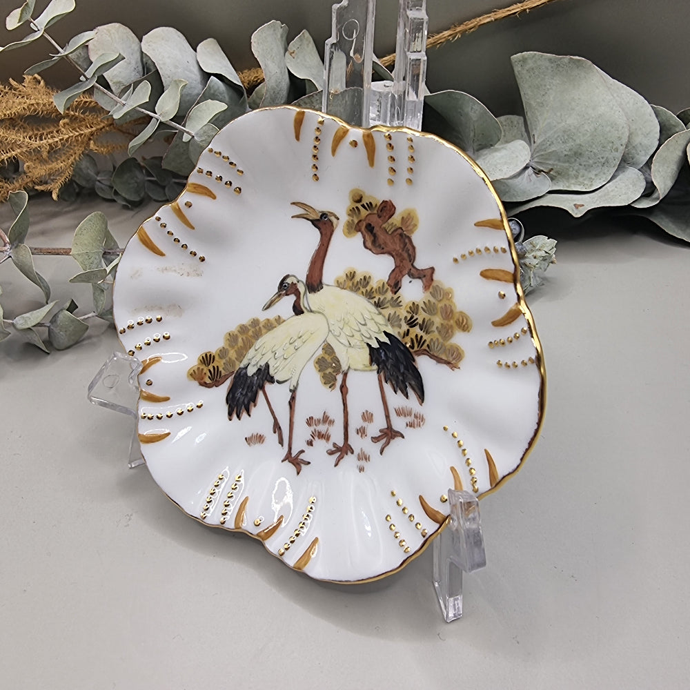Scalloped porcelain dish with painted cranes and gold detailing.