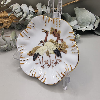 Scalloped porcelain dish with painted cranes and gold detailing.