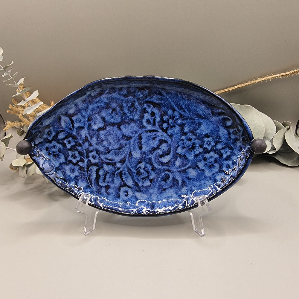 Deep blue ceramic dish with embossed floral pattern and round end handles.