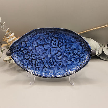 Deep blue ceramic dish with embossed floral pattern and round end handles.