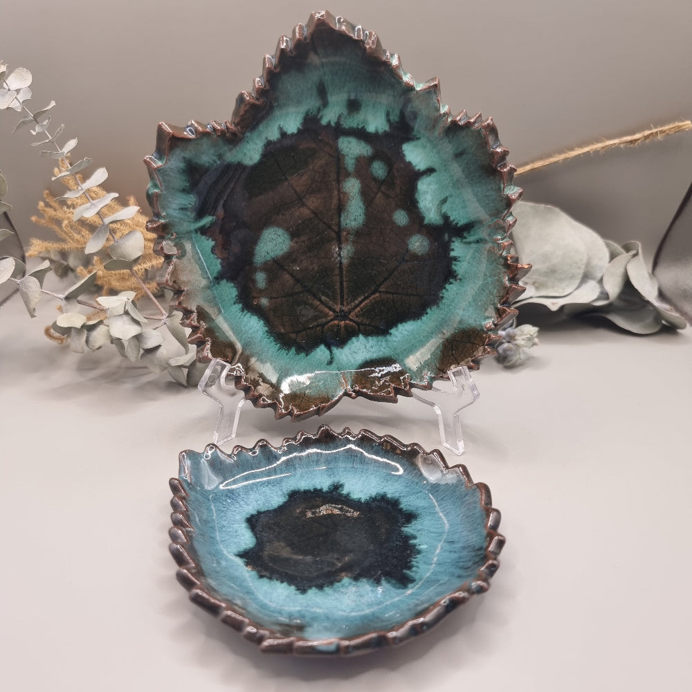 Set of 2 maple leaf-shaped ceramic dishes in teal and brown glaze with textured detail.