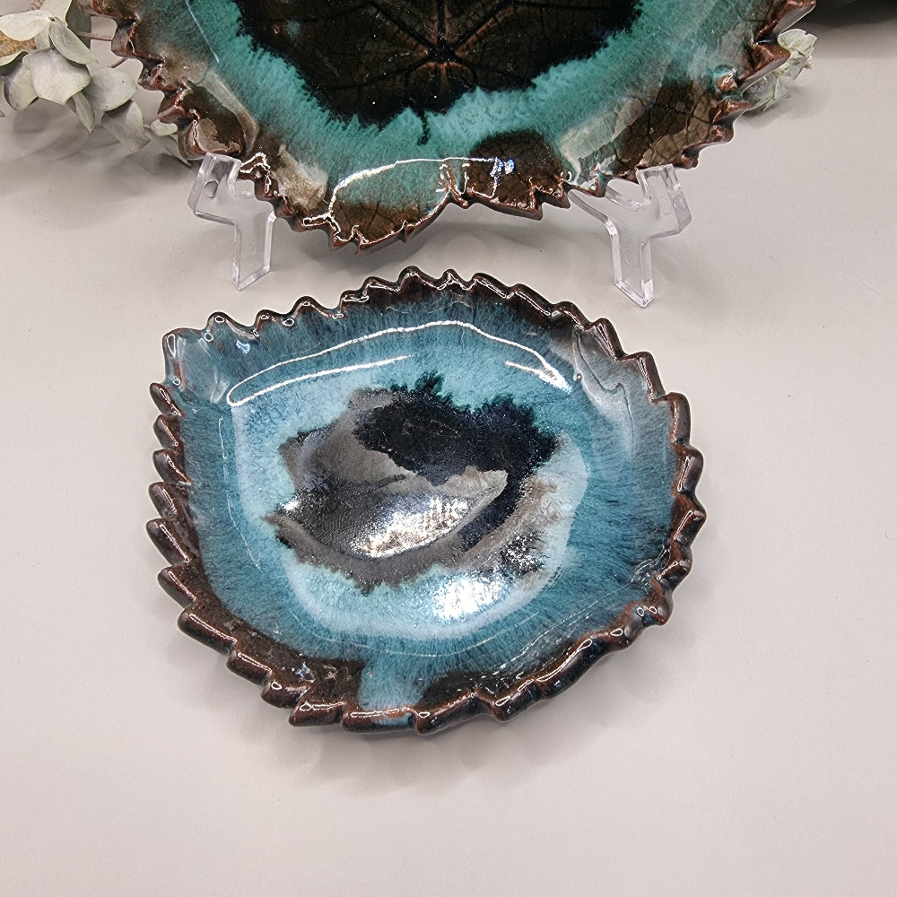 Set of 2 maple leaf-shaped ceramic dishes in teal and brown glaze with textured detail.