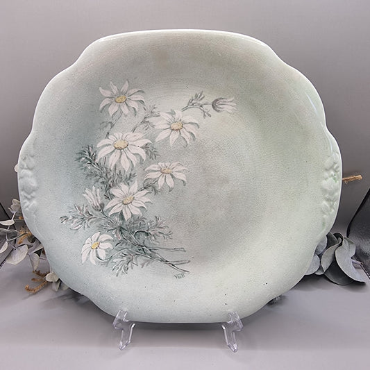 Pale green ceramic plate with hand-painted white daisies, scalloped edge, and vintage finish.