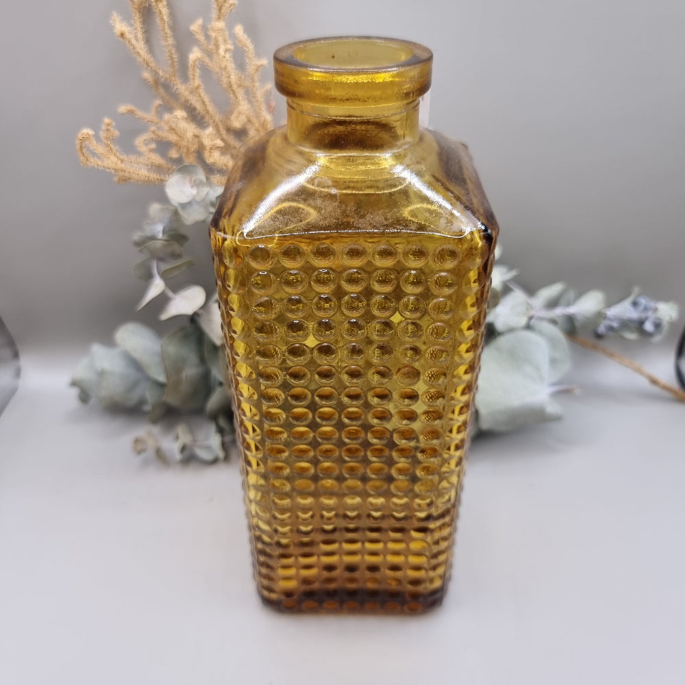 Amber textured glass bottle vase with honeycomb-style dots and squared shape, perfect for flowers or decor.