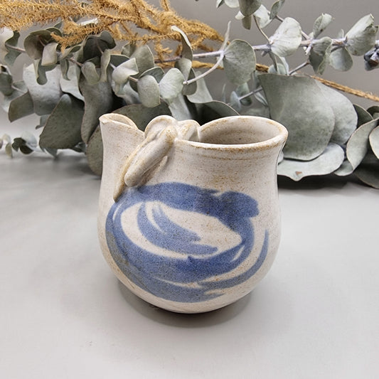 Handmade blue and white ceramic jug with bow detail and painted swirl pattern.