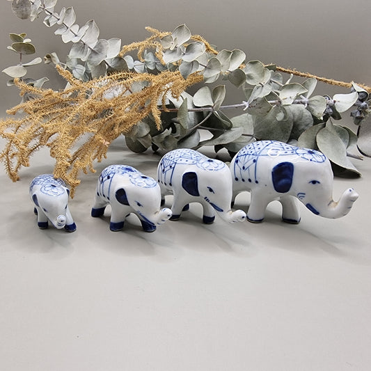 Set of 4 miniature blue and white porcelain elephants with raised trunks and painted blankets.