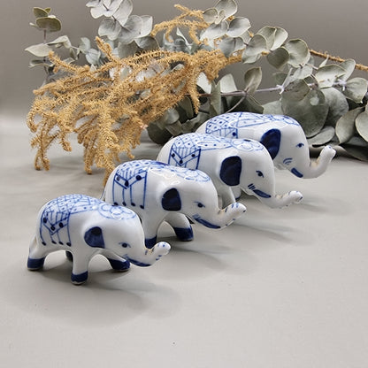 Set of 4 miniature blue and white porcelain elephants with raised trunks and painted blankets.