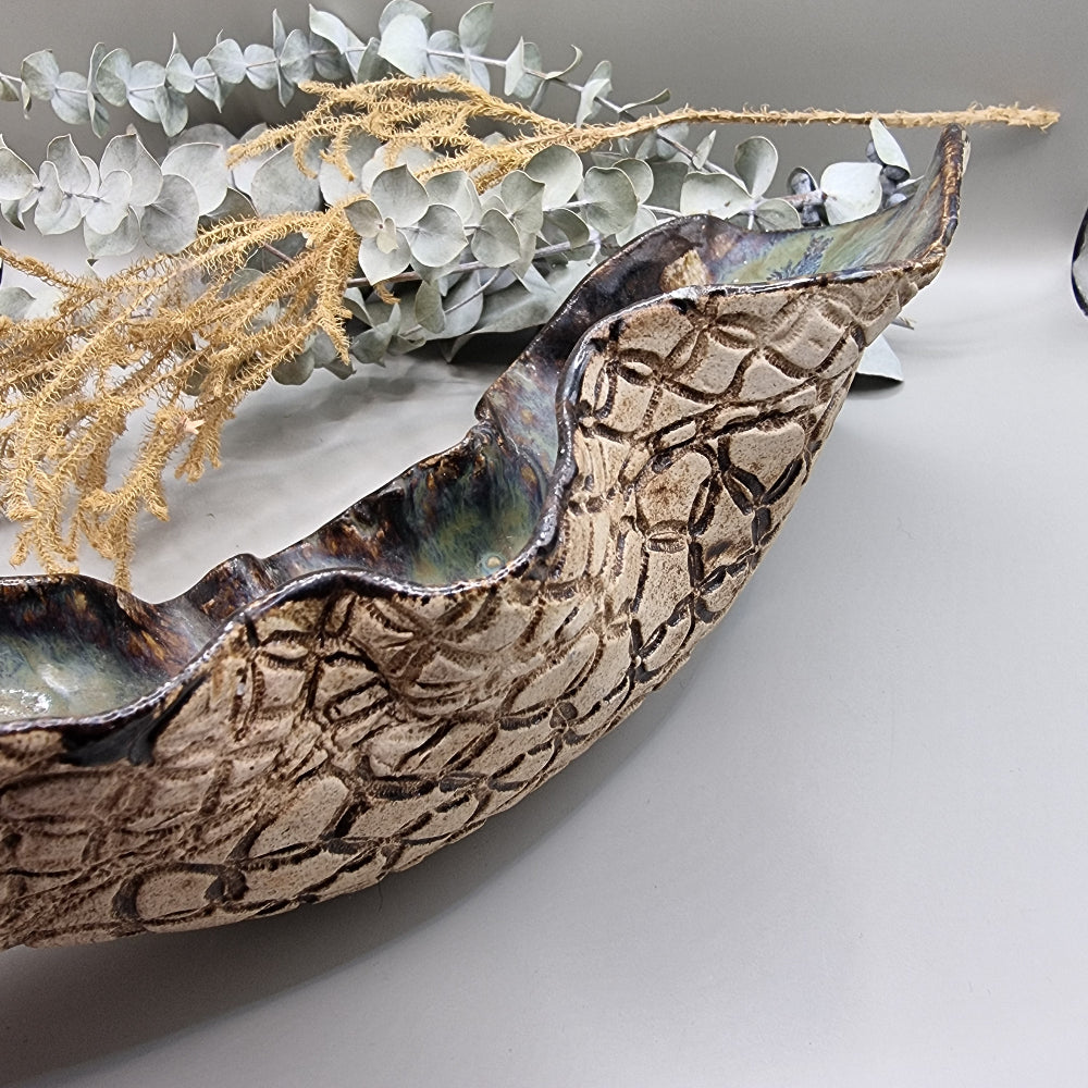 Handmade ceramic bowl with flowing form, sea-toned glaze, and textured outer surface.