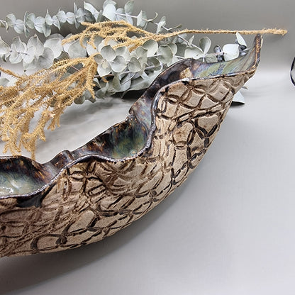 Handmade ceramic bowl with flowing form, sea-toned glaze, and textured outer surface.
