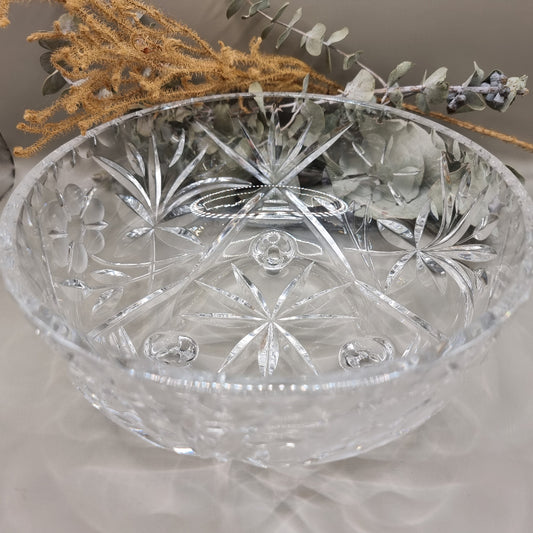 Clear footed glass bowl with starburst and floral cut-style patterns.