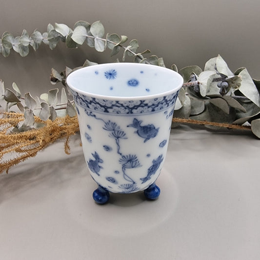 Footed Japanese porcelain sake cup with blue and white goldfish and lotus design.